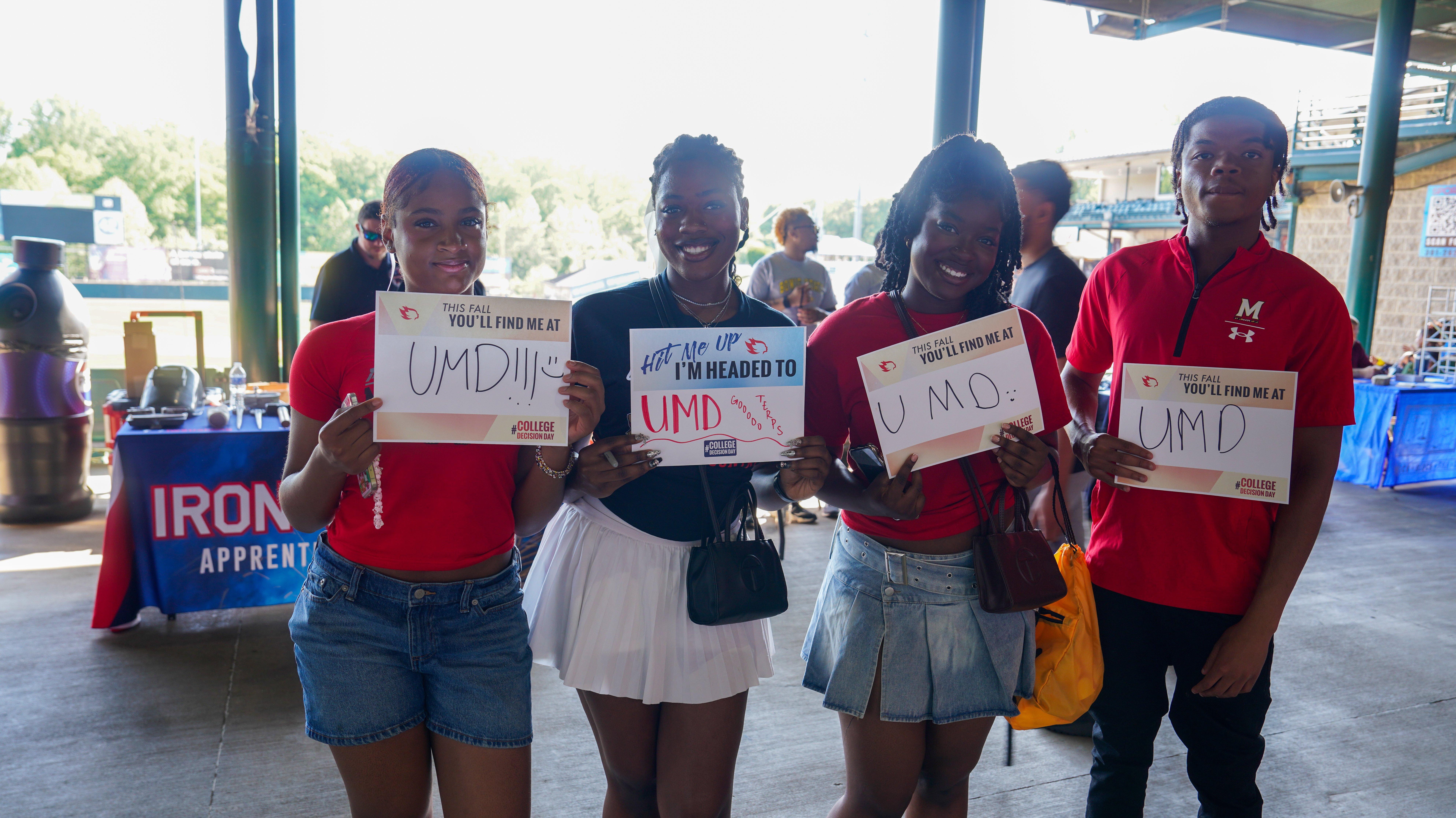 Four Students Holding UMD Signs.jpg