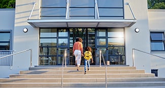 adult walking child up steps in front of building